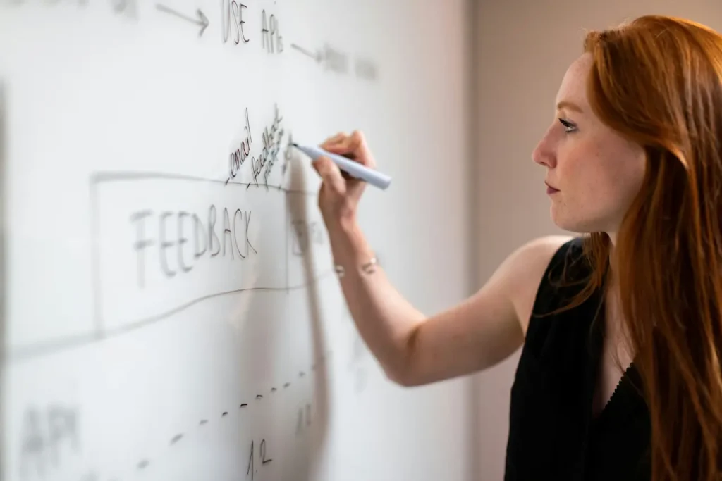 Atelier de communications stratégiques, une femme trace un schéma de flux au marqueur sur un tableau blanc