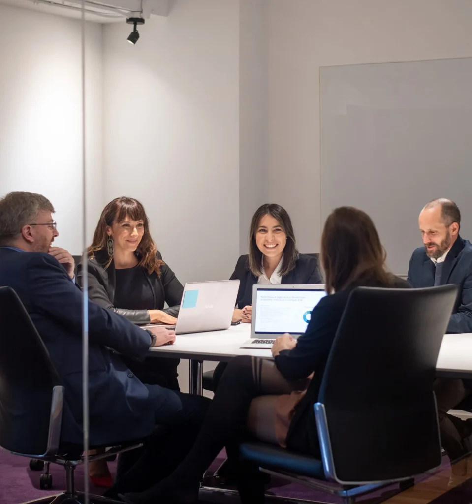 Équipe de direction réunie autour d'une table avec ordinateurs portables et présentation affichée à l'écran