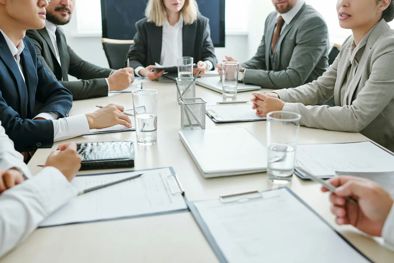 Membres d'un conseil d'administration autour d'une table de conférence avec documents et verres d'eau